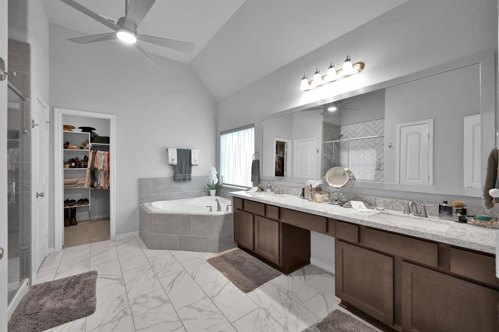 This is a spacious, modern primary bathroom featuring dual-sinks with ample storage.