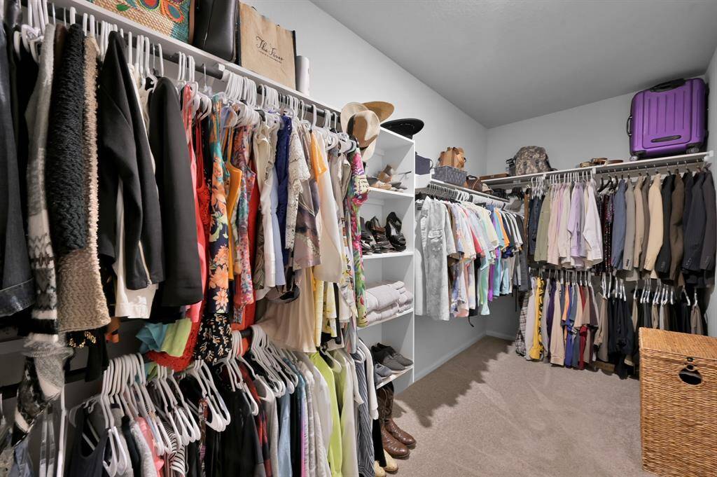 This spacious walk-in closet features ample hanging space, shelving for shoes and accessories.