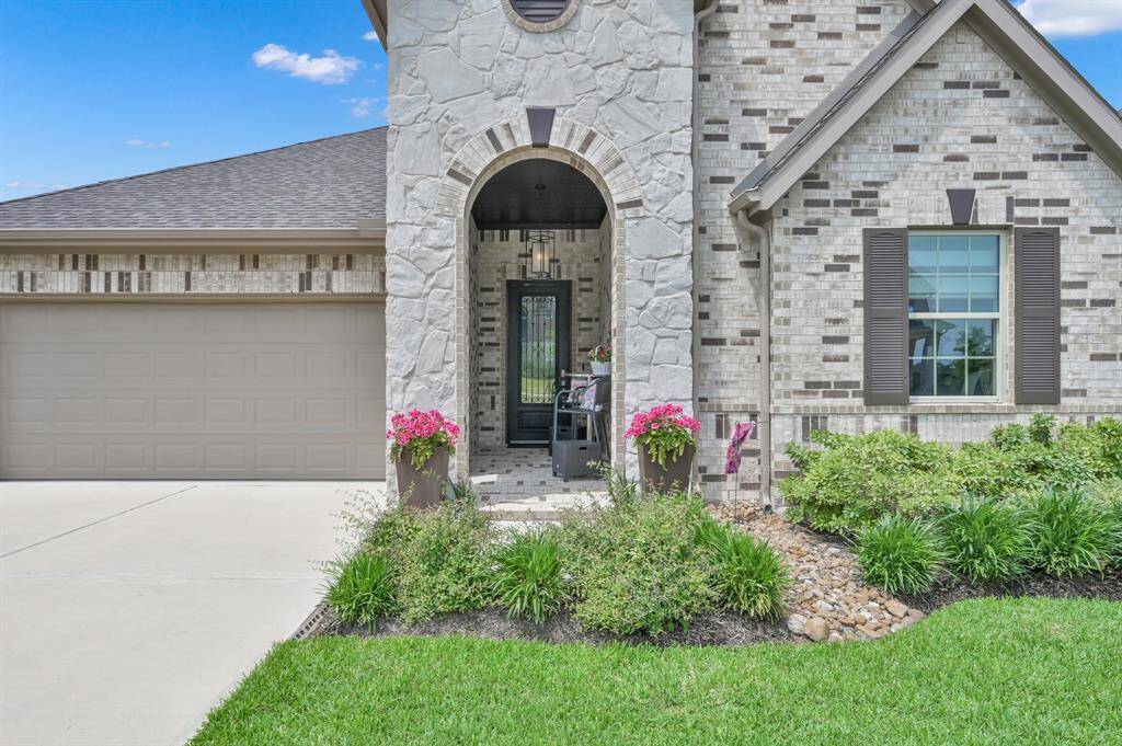 Welcoming arched entryway. Well-maintained landscape with vibrant flowers and greenery. Includes a spacious garage and a cozy front porch.