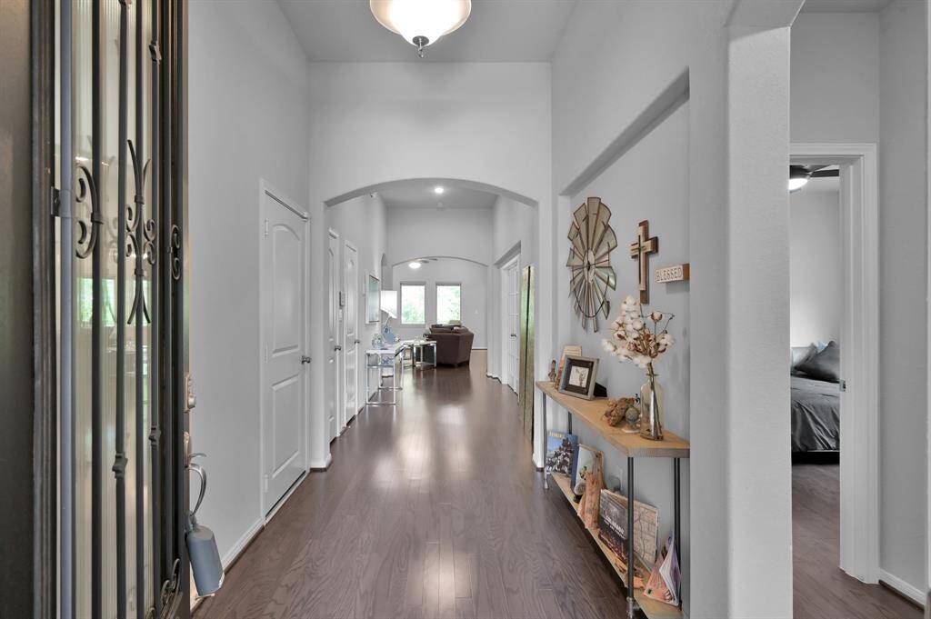 This photo showcases a bright, inviting hallway with wood flooring and decorative accents on the walls. The space leads to a living area with ample natural light.