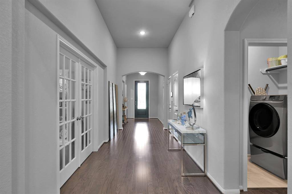 Bright, spacious hallway with wood flooring, leading to the living room.