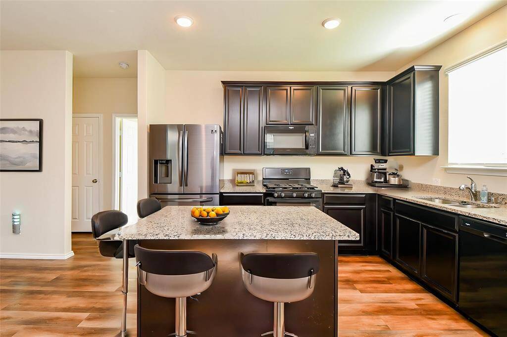 Discover a chef's dream in this stylish and functional kitchen. Imagine preparing culinary delights amidst the sleek, dark cabinetry that offers abundant storage for all of your essentials.