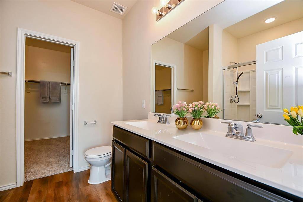 Discover this well-designed en-suite bath, the sleek countertops and dark cabinetry offer a touch of modern elegance and storage.