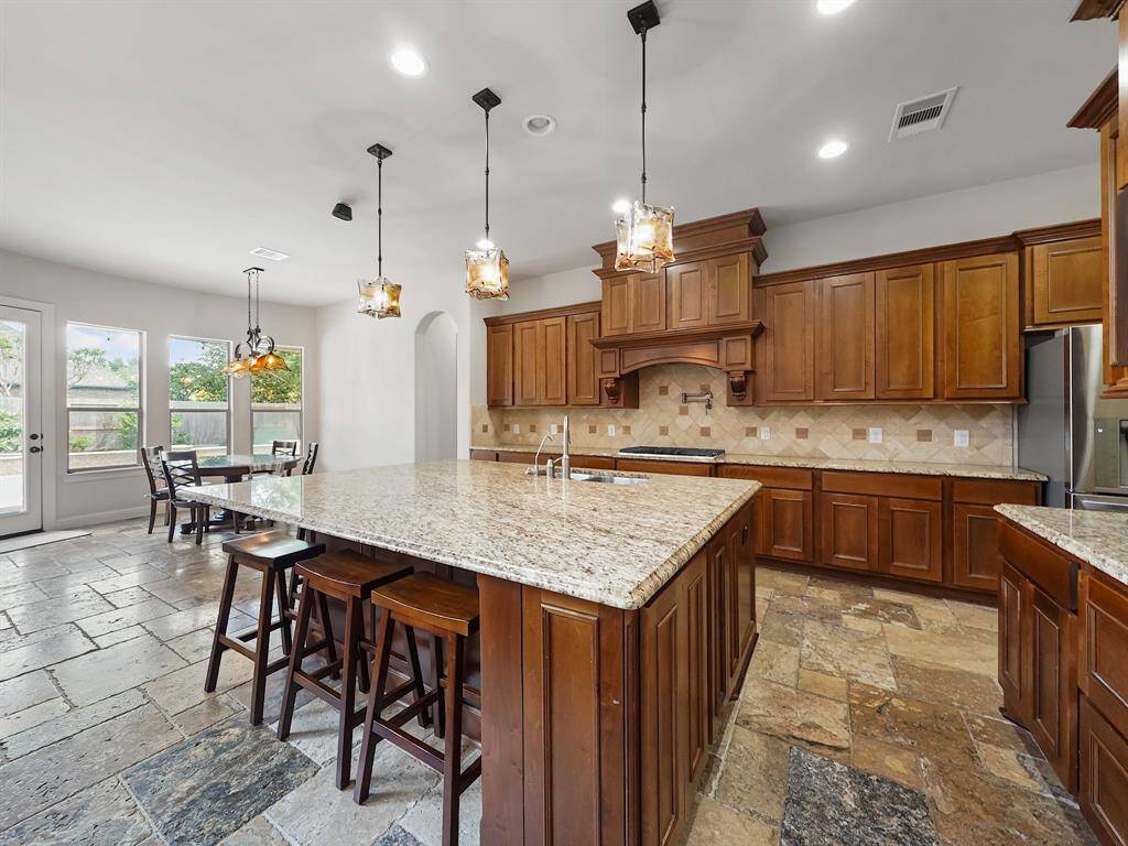 The oversized island provides additional seating, perfect for entertaining. Featuring top-of-the-line stainless steel appliances, including double ovens, this kitchen is a chef's delight.