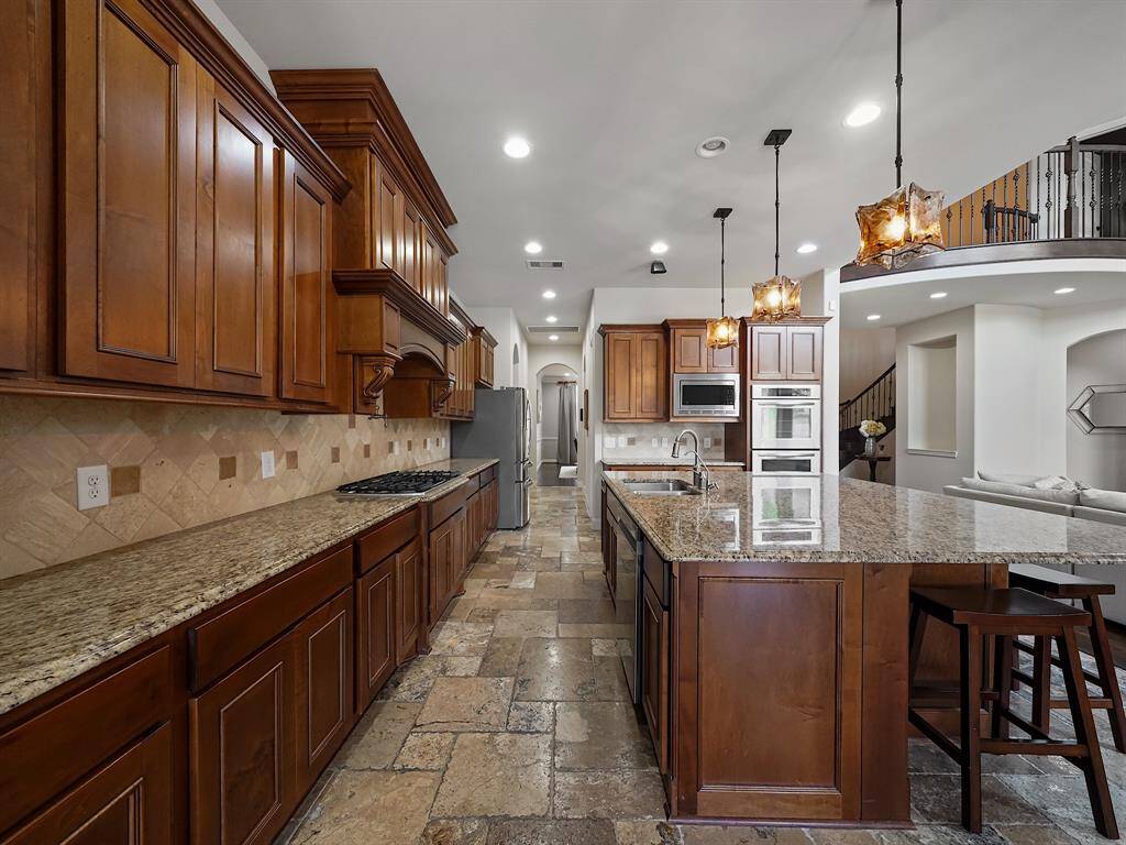 Elegant pendant lighting illuminates the island, while a convenient pot filler above the gas range adds a touch of luxury.