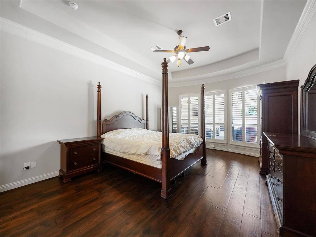 Escape to your primary retreat, a haven of luxury and tranquility. Featuring an elegant tray ceiling, sophisticated plantation shutters, and refined crown molding, this space exudes timeless charm. Enjoy the warmth and durability of engineered hardwood flooring underfoot. Your personal oasis awaits.