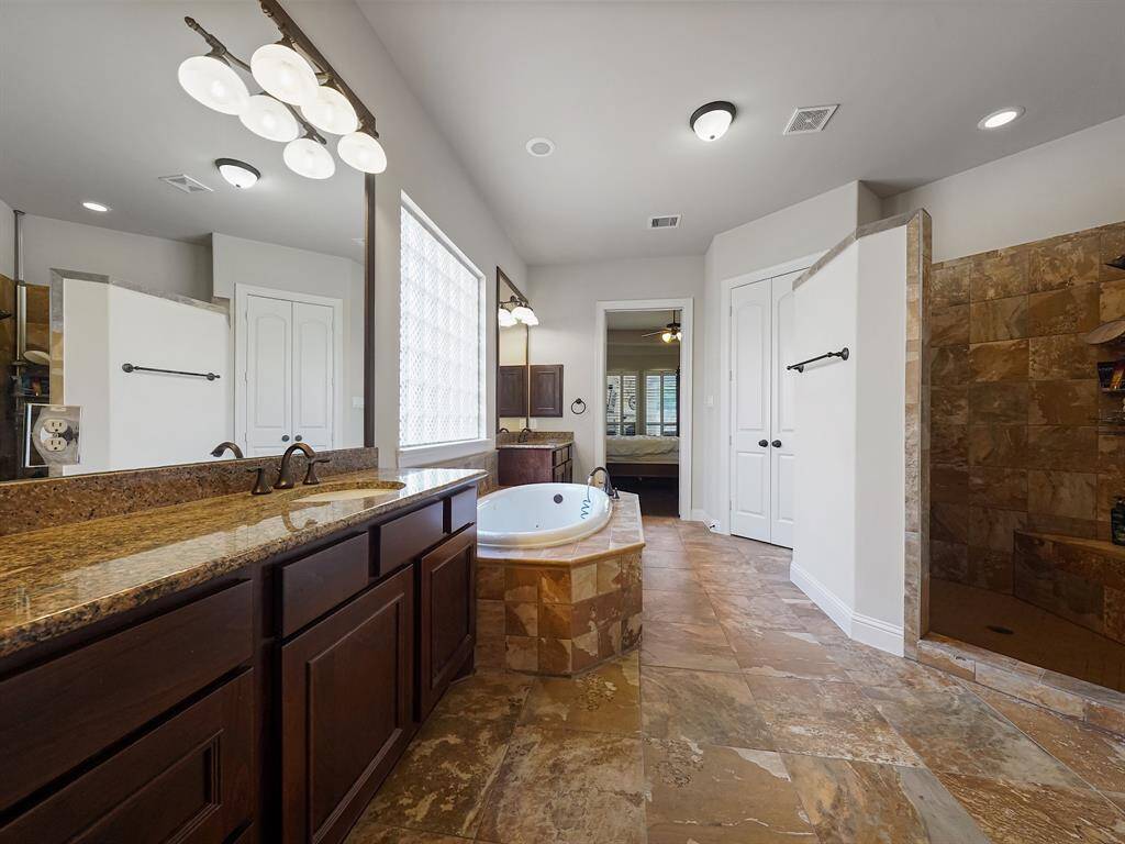 Step into a world of opulent tranquility in the luxurious master bath. Imagine beginning your day at the dual granite vanities, adorned with richly stained cabinetry, granite countertops, and elegant undermount sinks framed by exquisite mirrors. After a long day, escape to your personal oasis in the jetted tub, the perfect sanctuary for relaxation and unwinding. Enjoy the convenience of an oversized, walk-in shower with ample space!