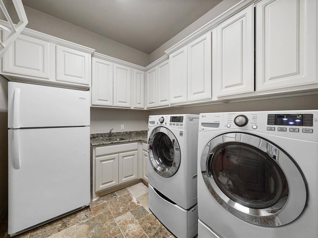 Enjoy the convenience of a large utility room featuring extensive cabinet storage, ideal for keeping your home organized. The room also provides ample space for a refrigerator and is equipped with a practical utility sink, enhancing its functionality.