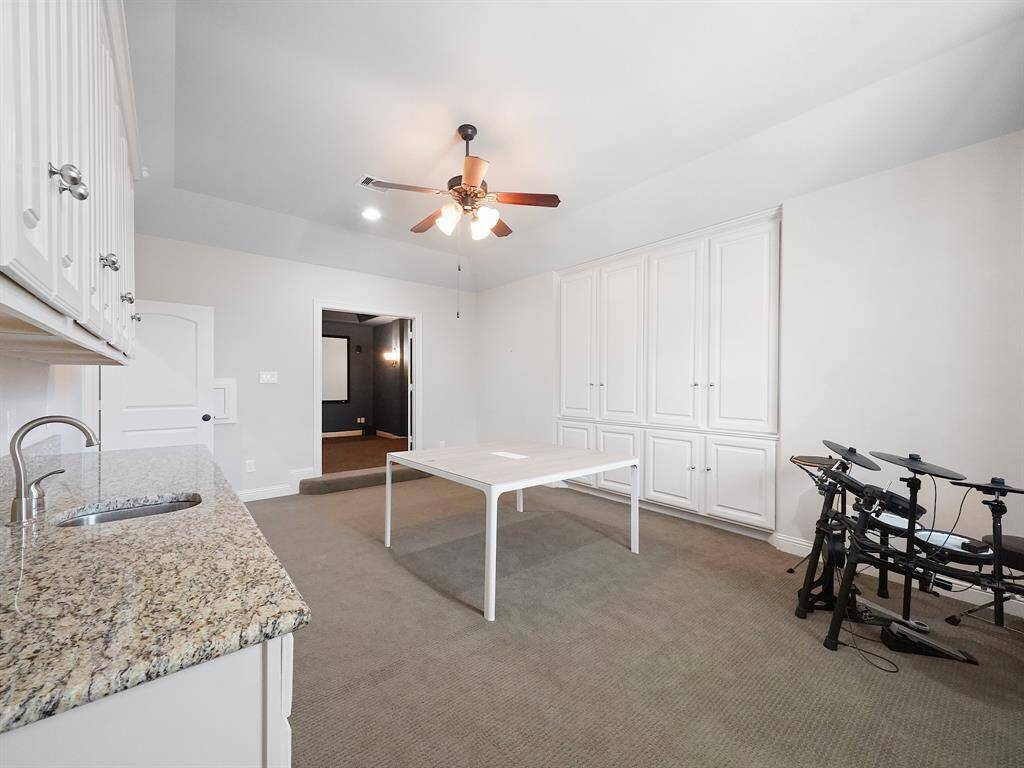 A well-appointed kitchenette enhances the game room's appeal making it an ideal setting for hosting memorable game nights and social gatherings. The game room seamlessly flows into the adjacent media room, providing a cohesive entertainment area. A cleverly concealed laundry chute behind the door offers direct access to the laundry room below, adding convenience to everyday living.