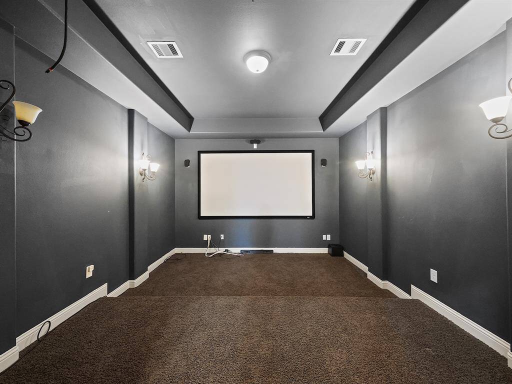 Experience unforgettable movie nights in this dedicated media room. The dark walls and coffered ceiling create an immersive and sophisticated atmosphere, enhanced by elegant wall sconces. This space is perfectly designed for memorable gatherings with friends and family.