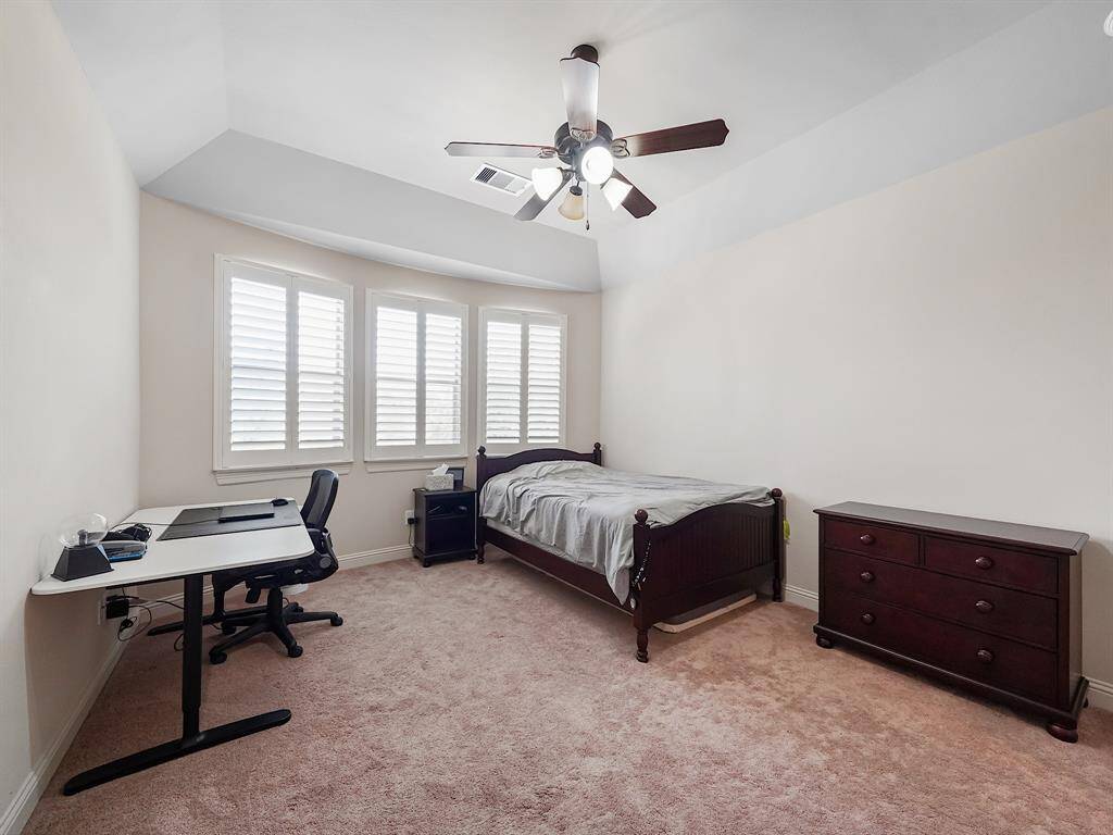 Welcome to this charming secondary bedroom located on the third floor. This inviting space features a vaulted ceiling, plantation shutters for optimal light control and privacy, a ceiling fan for added comfort, and a generously sized closet to meet all your storage needs.