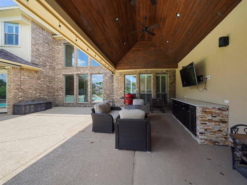 This inviting patio boasts a beautiful wood ceiling and a strategically placed ceiling fan for optimal comfort. The generous space offers endless possibilities for creating the perfect outdoor entertainment zone. Envision hosting unforgettable gatherings or simply unwinding after a long day in this versatile and stylish setting.