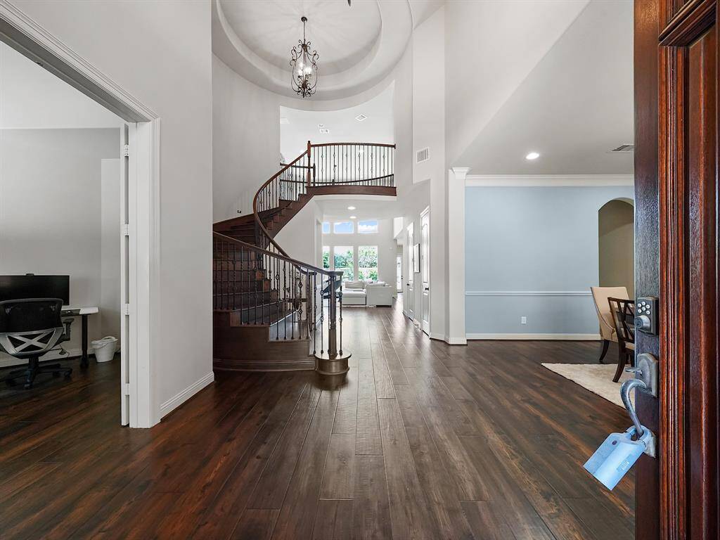 The grand two-story foyer, adorned with a circular staircase, sets a tone of sophistication and elegance upon entry. Hardwood flooring flows seamlessly throughout the main living areas, adding warmth and richness to the interior.