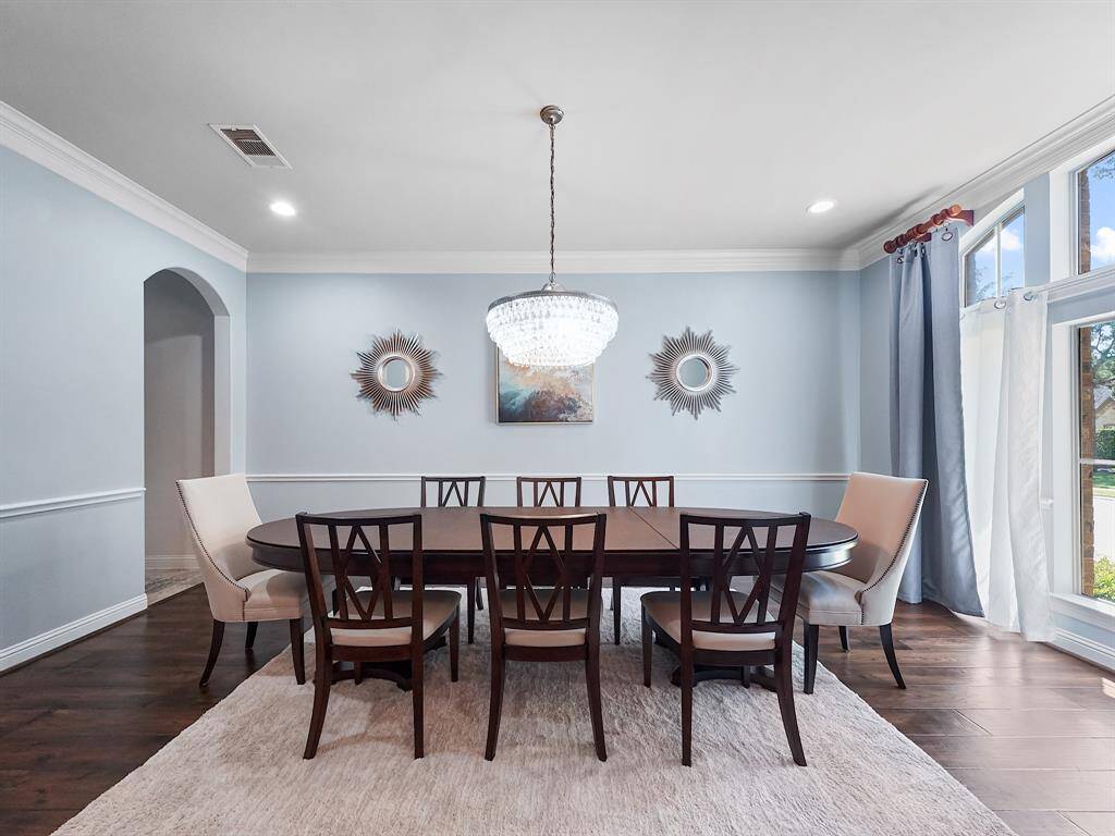 The formal dining room exudes refinement, featuring crown molding, an arched window, chair rail accents, and an exquisite chandelier, perfect for hosting memorable gatherings.