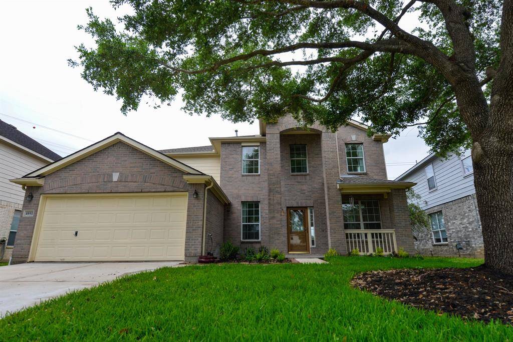 Elegant brick home nestled among mature trees, offering timeless charm and serene surroundings.