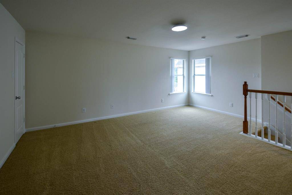 This spacious upstairs study can easily convert to a fifth bedroom, with private access to the owner's suite and an opening to the game room for versatile living.