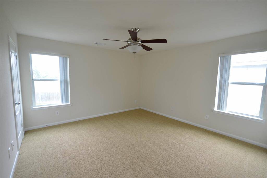 Bright bedroom with ample windows and a ceiling fan for comfort.