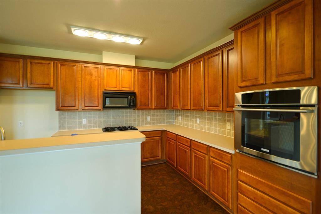 This kitchen boasts ample cabinets, a gas range, a stainless steel oven, and generous counter space.