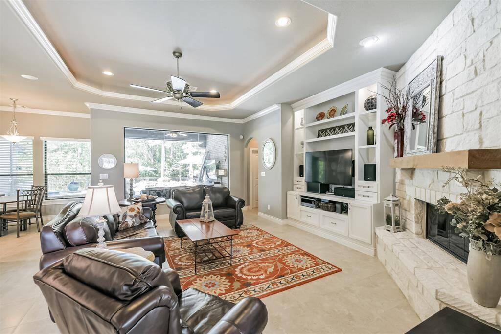 Welcome to a beautifully designed living room where warmth and elegance meet. Enjoy the natural light streaming through the large, fixed-pane window that offers serene views of the backyard.