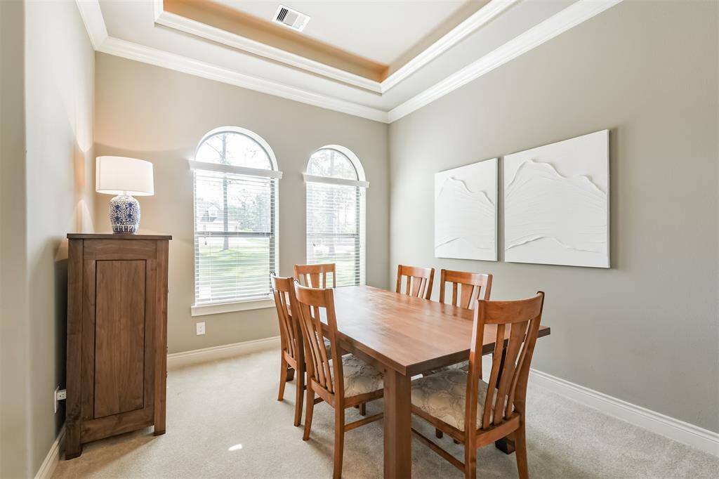 The formal dining room features elegant tray ceilings, detailed crown molding, and arched windows that flood the space with natural light. The open layout flows seamlessly into the living area, making it perfect for entertaining.