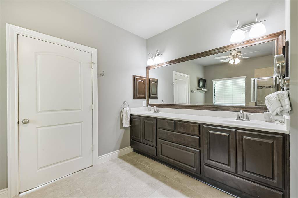 The luxurious primary bathroom is a serene retreat featuring a spacious double vanity with rich cabinetry, sleek fixtures, and a framed mirror that adds a touch of elegance. The large walk-in shower, soaking tub, and neutral tile floors create a spa-like atmosphere. A private water closet adds convenience, while the expansive walk-in closet with natural light and custom shelving offers ample storage and organization.