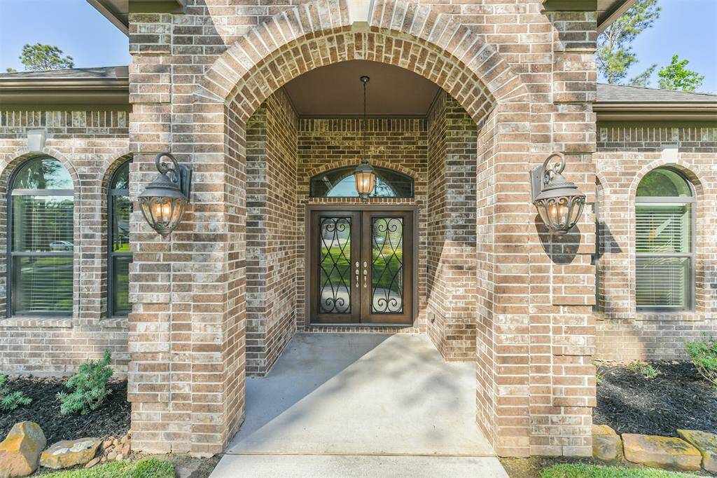 Step into timeless elegance through this stunning arched brick entryway, featuring custom wrought iron double doors and warm lantern-style lighting. The covered front porch offers a gracious welcome, setting the tone for the quality and craftsmanship found throughout the home. A beautiful blend of charm and sophistication greets you right at the front door.