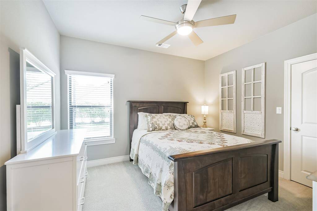 This charming secondary bedroom offers a bright and cozy retreat, perfect for guests or family. Soft neutral tones, plush carpet, and a modern ceiling fan create a calming atmosphere, while large windows fill the space with natural light. Thoughtful details and generous closet space make it as functional as it is welcoming.
