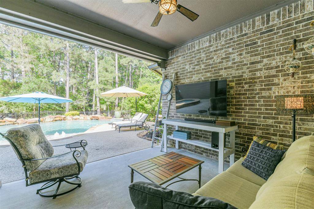 Enjoy the best of outdoor living under the covered patio—complete with dual ceiling fans, space for a wall-mounted TV, and peaceful views of the resort-style pool. With lush woods as your backdrop and multiple seating areas, this space is made for relaxing or entertaining.