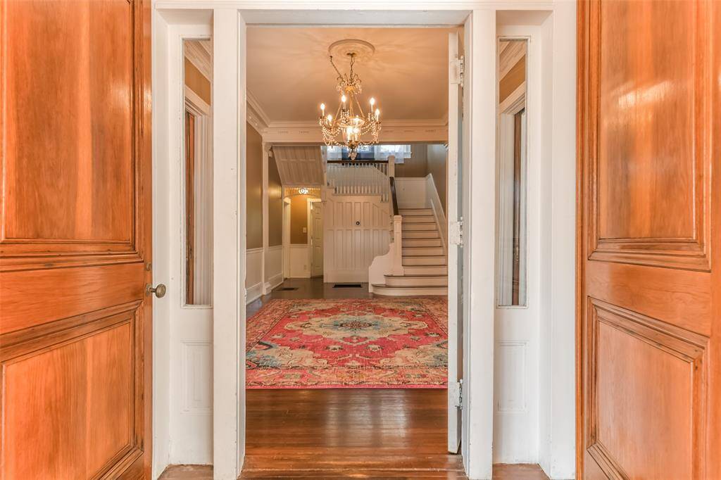 Step through the classic double doors from the inviting front porch and be welcomed by a grand staircase that anchors a spacious and elegant entryway, perfect for greeting guests in style.