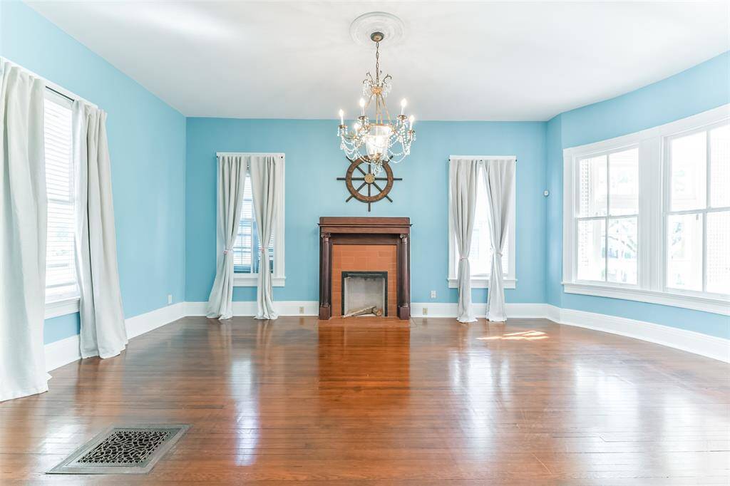 Discover the charm of this spacious room, one of two grand front-facing spaces featuring elegant pocket doors and a fireplace. Perfect for a living or dining area boasting beautifully preserved hardwood floors.