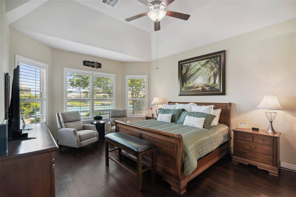 This primary bedroom has the perfect view of the water through bay windows and plantation shutters.