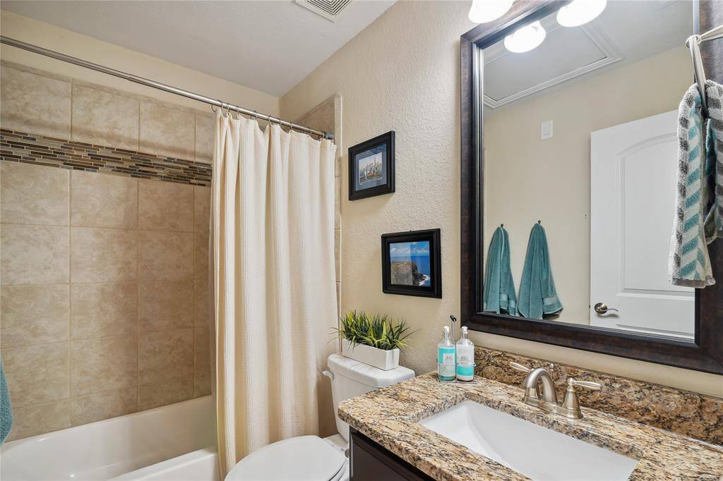 Upstairs Bathroom with granite top, framed mirror, tub and shower.