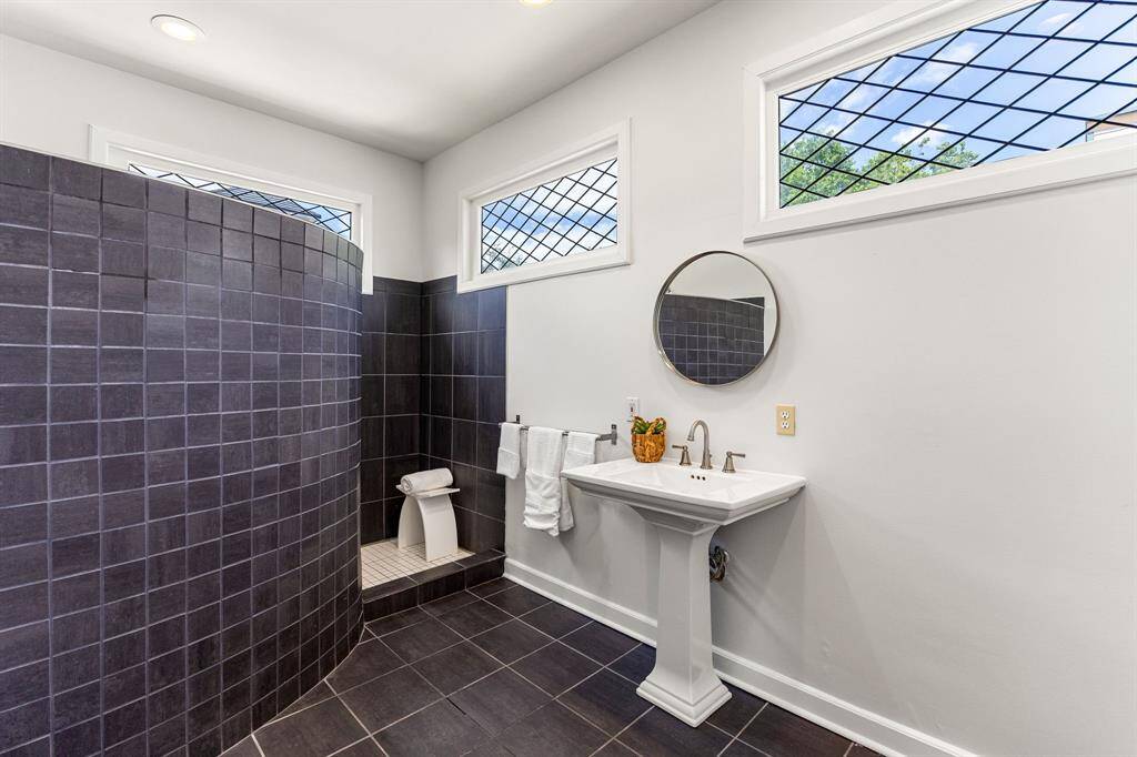 The primary bathroom features a large walk-in shower with custom curved tile wall. This bathroom has spa-like vibes!