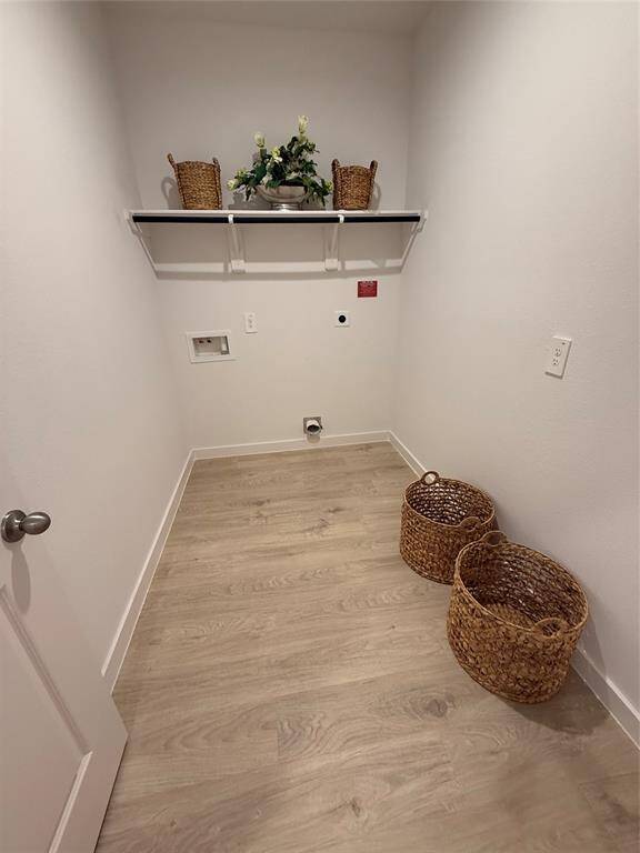This modern open-concept space features a sleek kitchen with white cabinetry, stainless steel appliances, and an island with bar seating. Adjacent is a stylish dining area with a glass table and contemporary chairs, all set on light wood flooring. The area is well-lit with recessed lighting, and there is a staircase leading to the upper level.