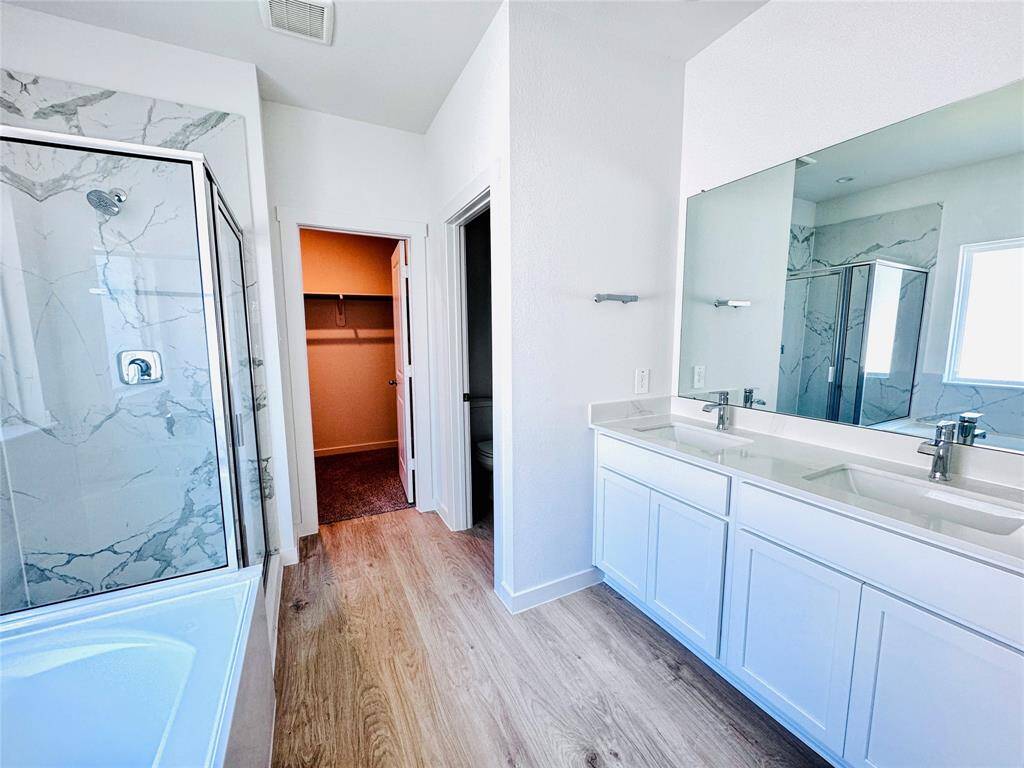 Luxuriate in a bathroom featuring dual vanities, a spacious walk-in shower, and a separate soaking tub.