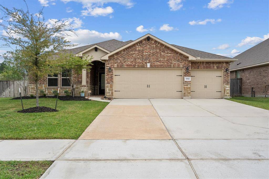 Charming home with a striking brick and stone facade, featuring a spacious 3-car garage and an extra-wide driveway for ample guest parking.