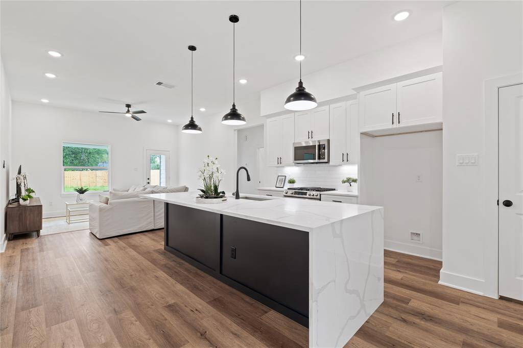 The kitchen features a large island with sleek quartz countertops and dark cabinetry, offering both style and functionality.