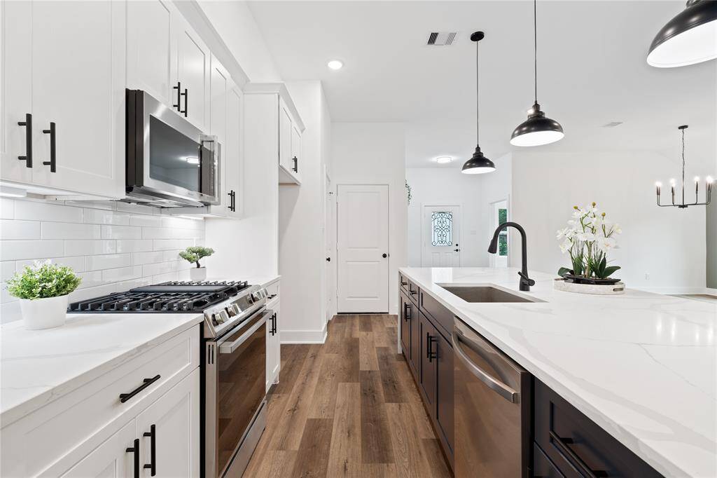This bright and modern kitchen creates a sophisticated contrast with clean white cabinets complemented by the dark finishes of the cabinet hardware.