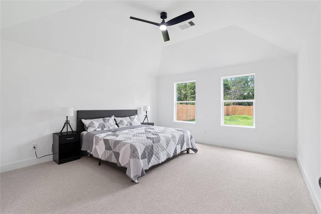 This spacious primary bedroom features high ceilings that enhance the open, airy feel of the room.