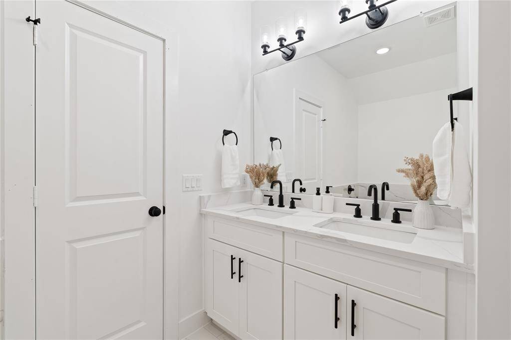 Elegant and functional, this primary bathroom features a spacious double vanity with sleek white cabinetry and stunning quartz countertops.