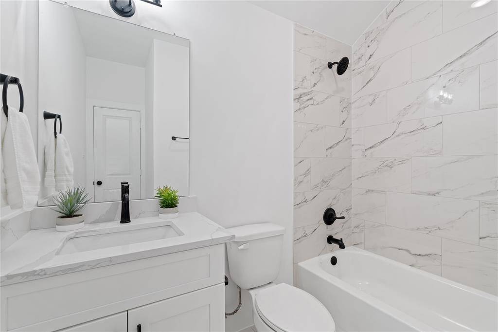 The stylish second bathroom comes complete with a shower/tub combo surrounded by elegant marble-finish tile.