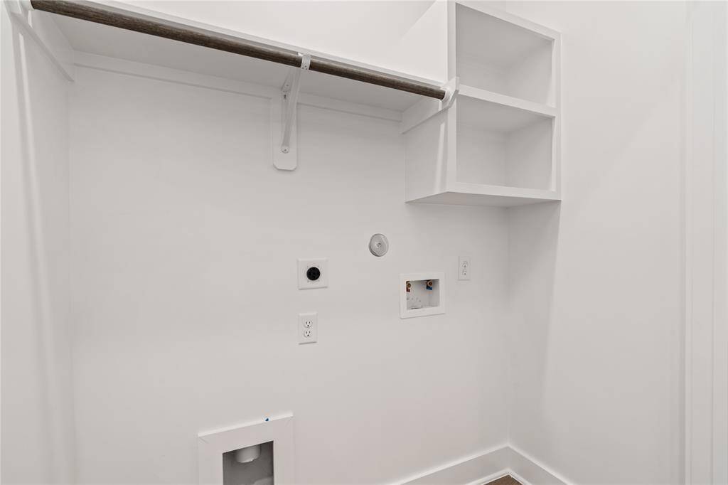 This functional utility room is designed for efficiency, featuring a built-in shelf for extra storage and a hanging rod for clothes.