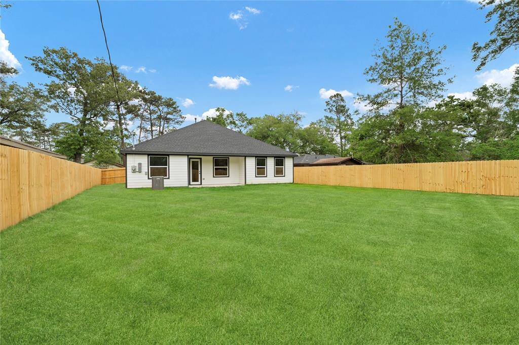 This backyard offers a large, lush lawn surrounded by a privacy fence, providing a peaceful and private outdoor space.