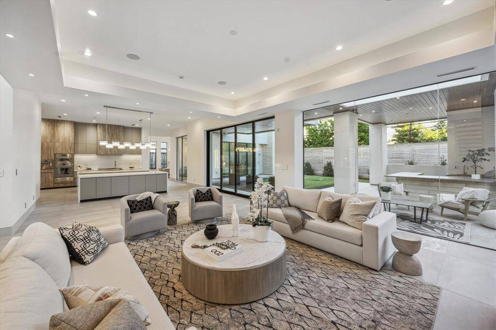 Living room with frameless wall of windows with views to backyard. Porcelain floors from Spain throughout downstairs