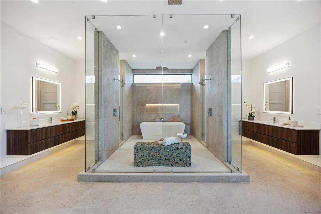 Primary bathroom with two floating sinks with illuminated mirrors