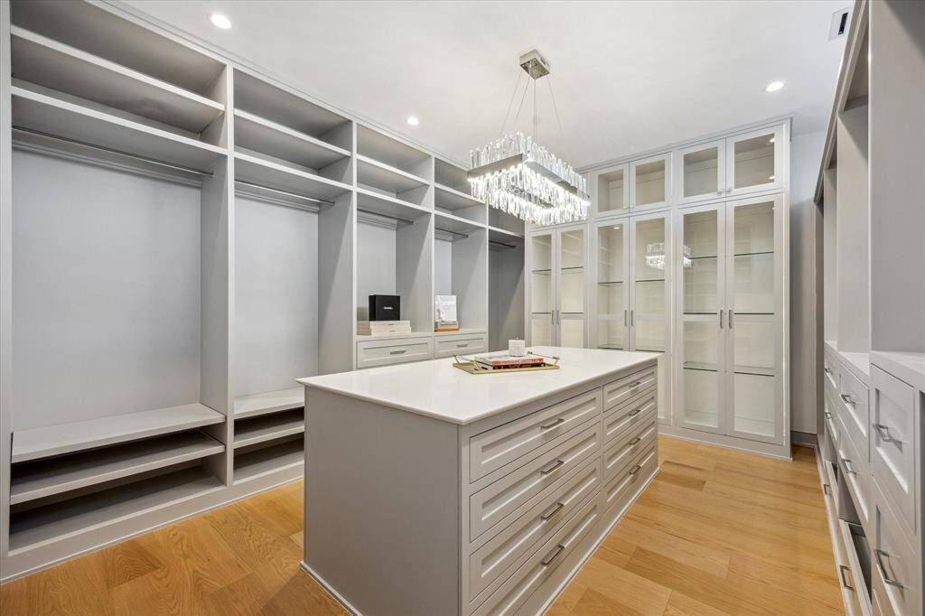 Primary closet #1 with packing island and glass front cabinets