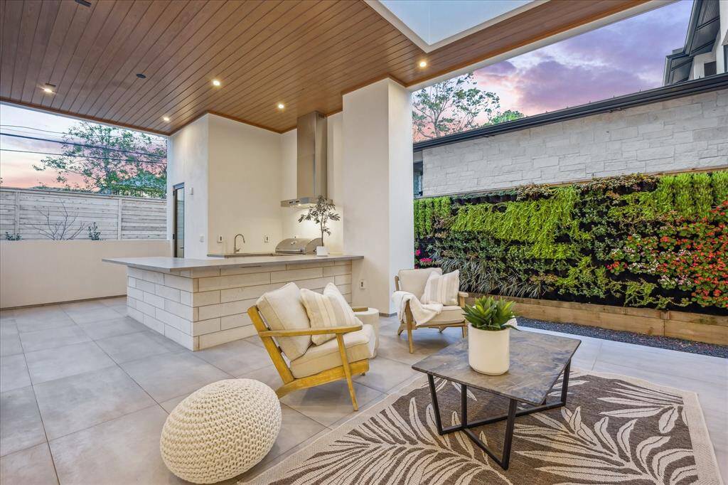 Outdoor patio space with vertical landscaping, summer kitchen, half bath, and outdoor shower