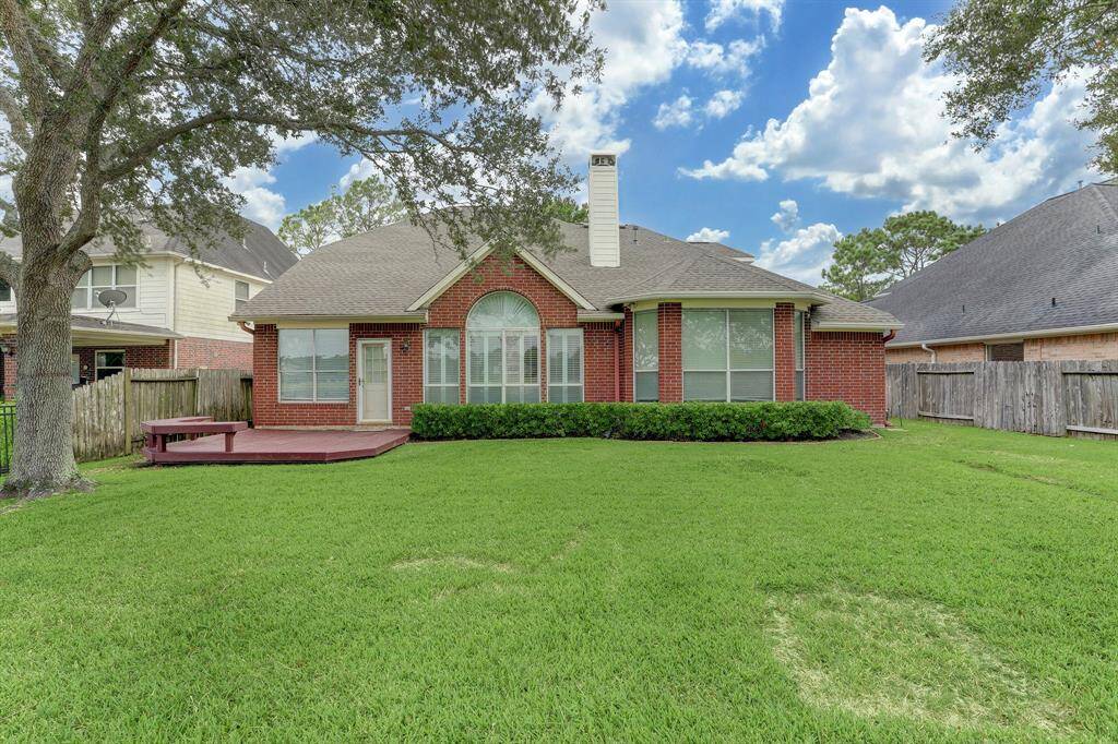 This charming brick home features a spacious backyard with a wooden deck, perfect for outdoor activities. The large windows offer plenty of natural light, and the well-maintained lawn is ideal for relaxation.