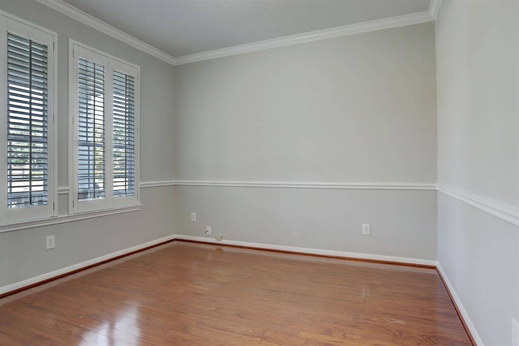 This bright, Office features hardwood floors, light gray walls, and large windows with white shutters, offering a clean and inviting space with ample natural light.