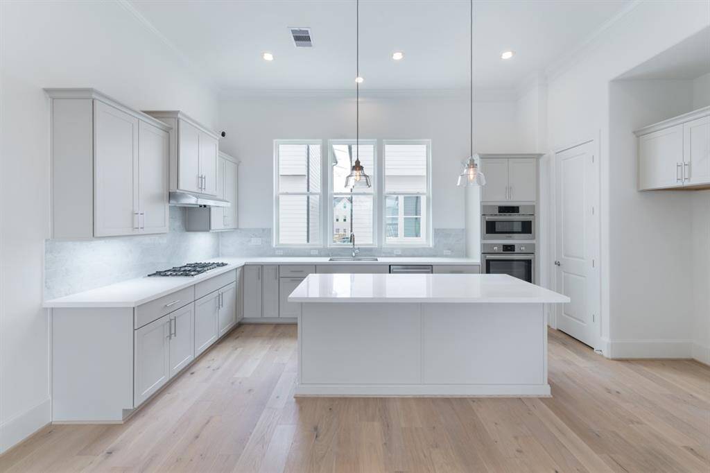 Bright tuxedo kitchen with luxe SS Bosch appliances, imperial white marble accents, and quartz countertops